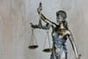 Bronze statue of Lady Justice wearing a blindfold and holding balanced scales, symbolizing fairness, impartiality, and the legal system, against a neutral background.