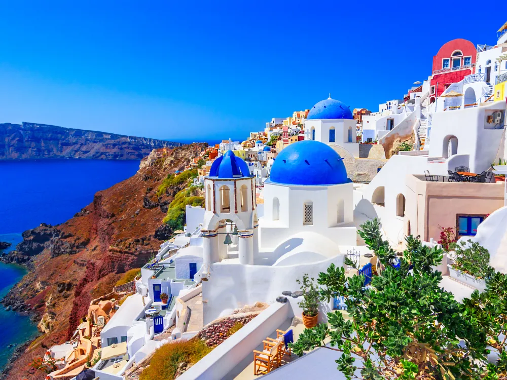 A vibrant view of Santorini, Greece, showcasing iconic white buildings with blue domes against a backdrop of deep blue sea and sky.