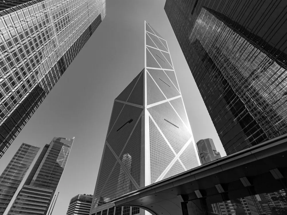 A striking black-and-white view of skyscrapers converging towards the sky, highlighting modern architecture and geometric designs.