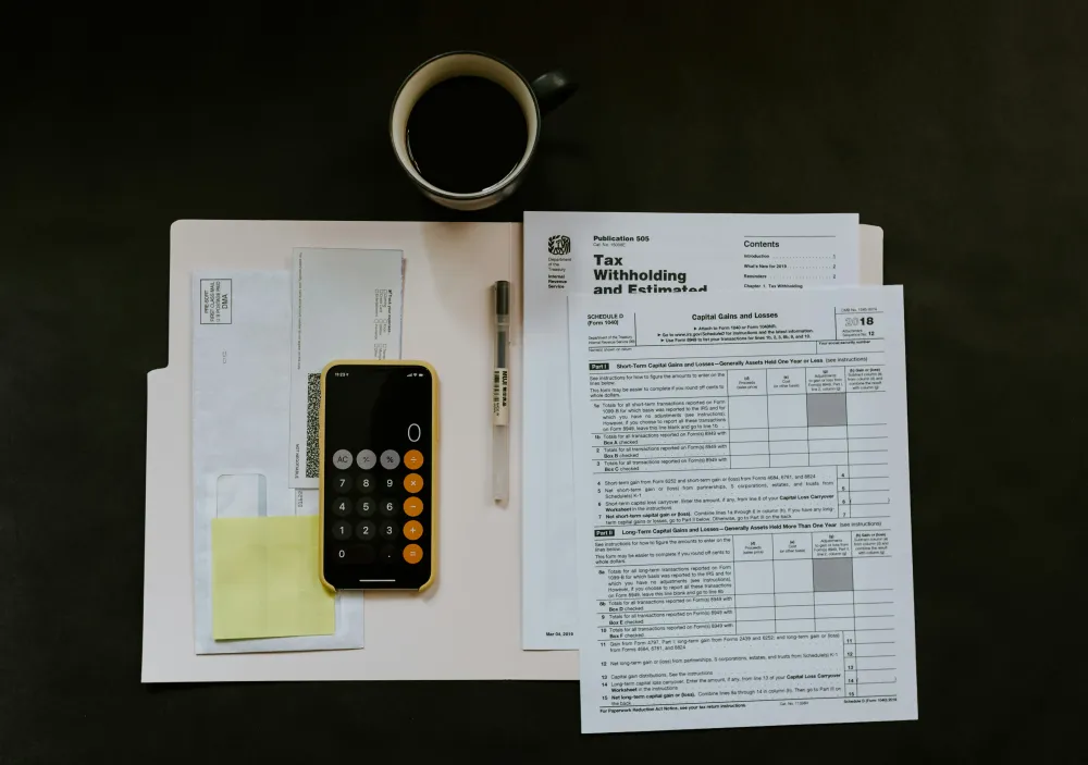  Tax forms and a calculator arranged on a wooden desk, indicating preparation for tax filing.  