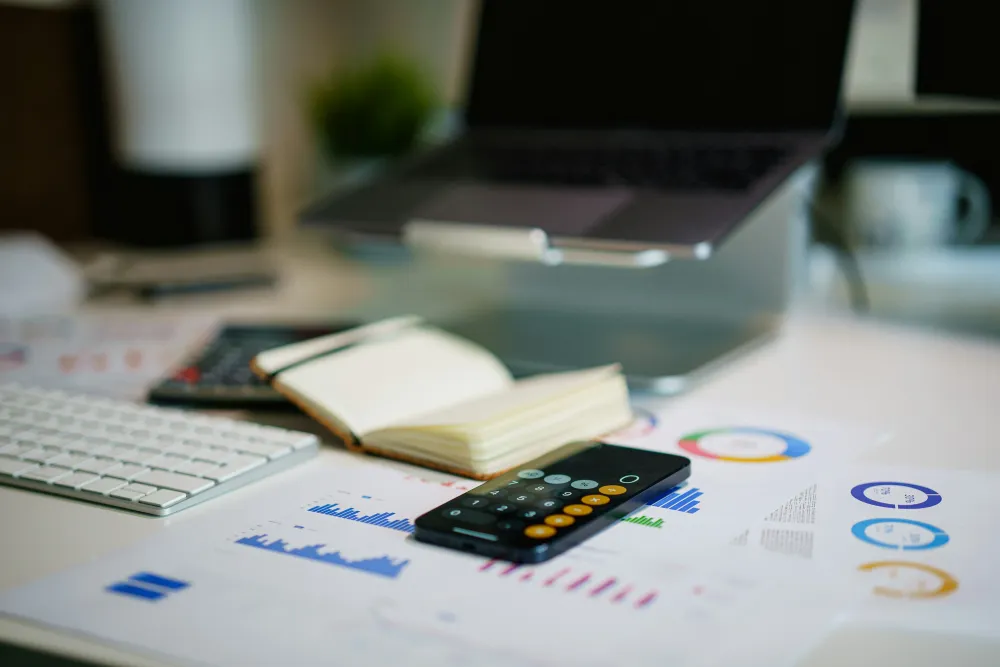 Modern workspace with financial charts, calculator, notebook, and laptop representing accounting, business analytics, and structured financial record management.