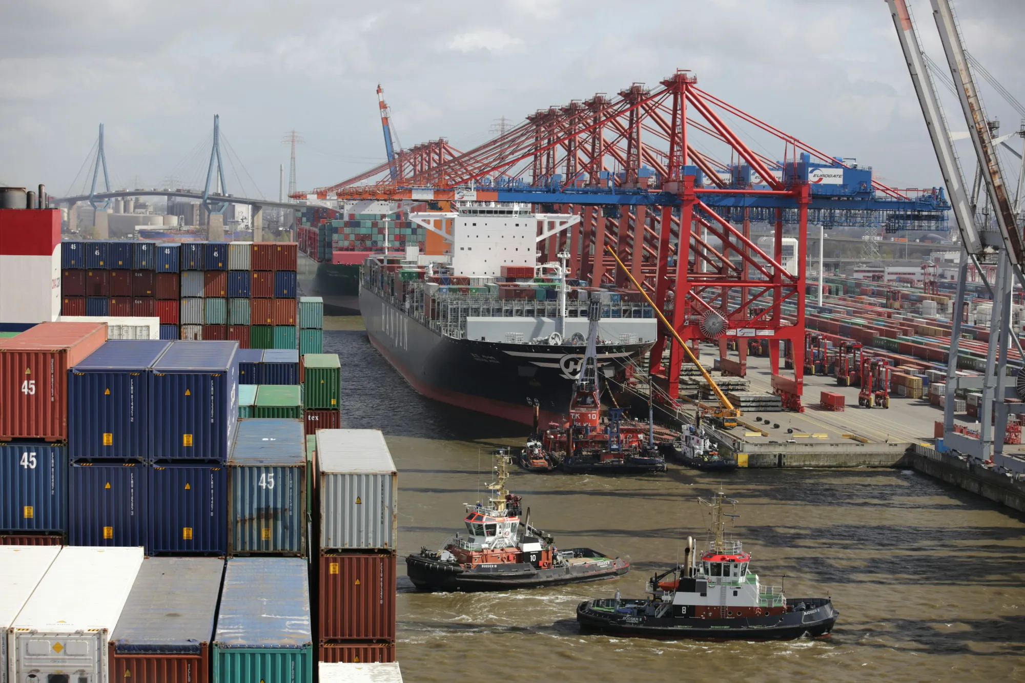 A shipping port with ships, containers and cranes.