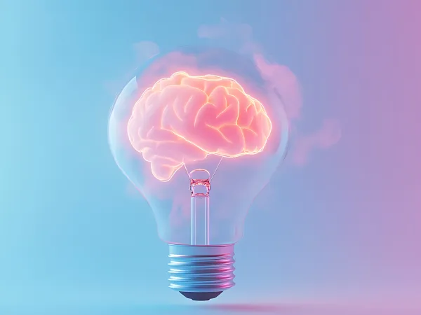 A glowing brain inside a light bulb against a gradient blue and pink background, symbolizing creativity and ideas.