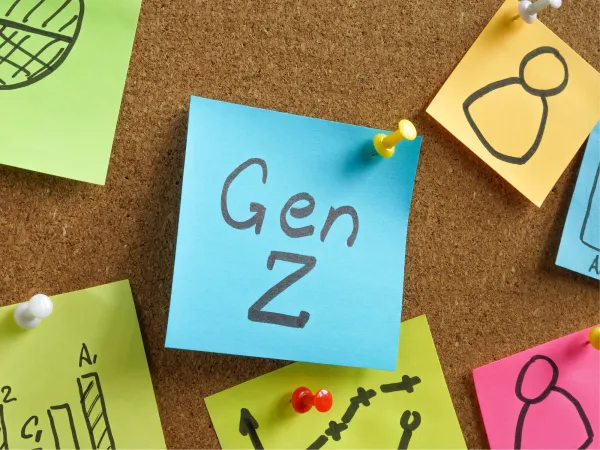 Colorful sticky notes on a corkboard, featuring the phrase "Gen Z" prominently on a blue note amidst various doodles and graphs.