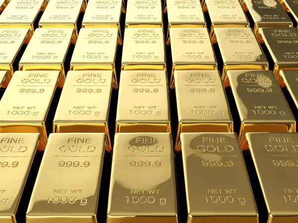 A close-up view of rows of shiny gold bars, each stamped with "FINE GOLD 999.9" and weighing 1000 grams.