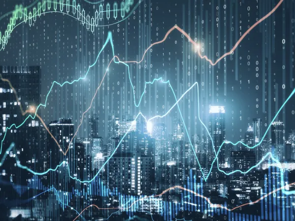 City skyline illuminated at night overlaid with digital graphs and binary code, representing finance and technology.