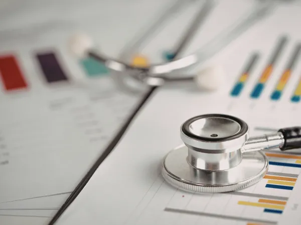 Stethoscope resting on financial charts and bar graphs illustrating the economic impact of medical negligence.