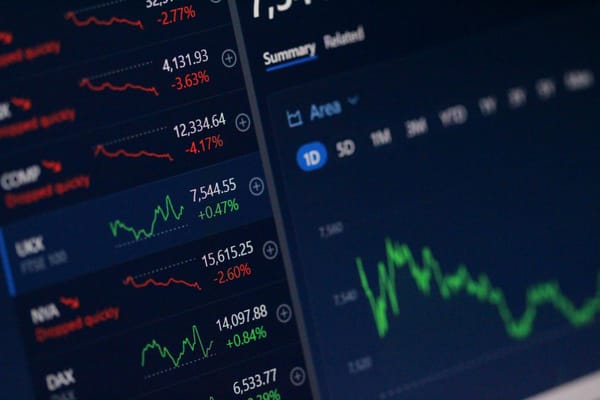 Close-up of a digital trading dashboard displaying stock market indices, percentage changes, and a live price chart on a computer screen.