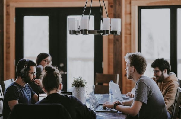 Developers working behind a shared table in an open work space. 