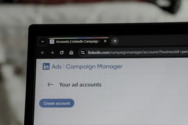 A laptop screen displaying the LinkedIn Ads Campaign Manager interface with a “Create account” button visible on the “Your ad accounts” page.